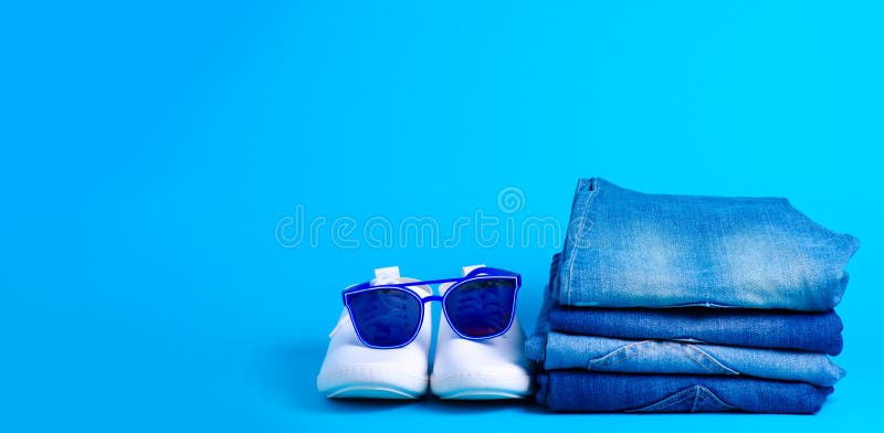 Stack folded jeans and sunglasses, white sneakers royalty free stock image
