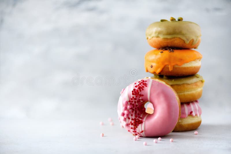 Stack of glazed colorful assorted donuts with sprinkles on grey cement background. Copy space. Sweet doughnuts for kids stock images Stack of glazed colorful assorted donuts with sprinkles on grey cement background. Copy space. Sweet doughnuts for kids stock images