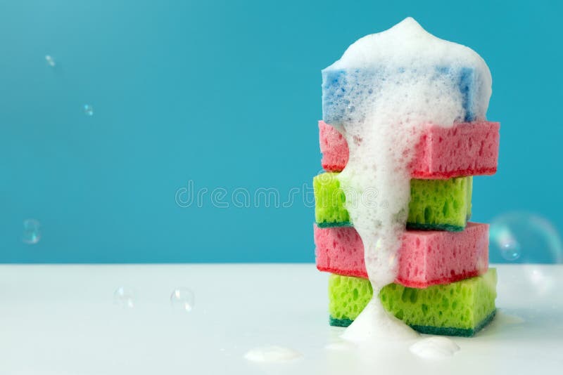 Stack of Kitchen Cleaning Sponges with Soap Bubbles on Blue Background