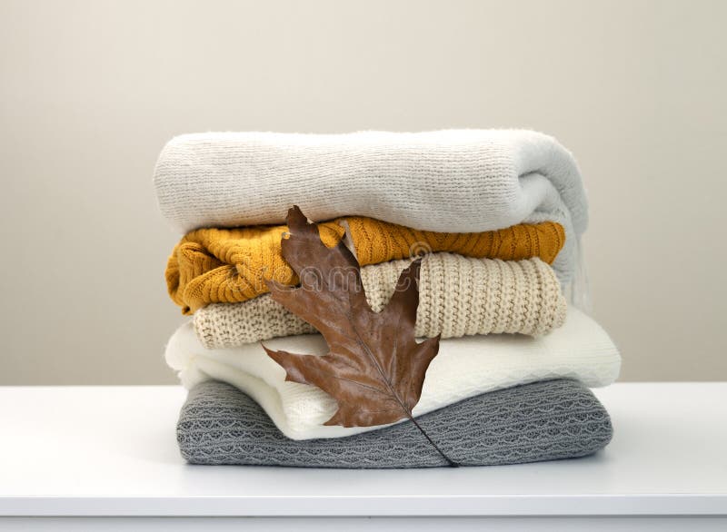 Stack of knitted clothes decorated with autumn leaf, woolen sweaters. Knitwear. Winter woolen clothes stock images, royalty-free photos and pictures