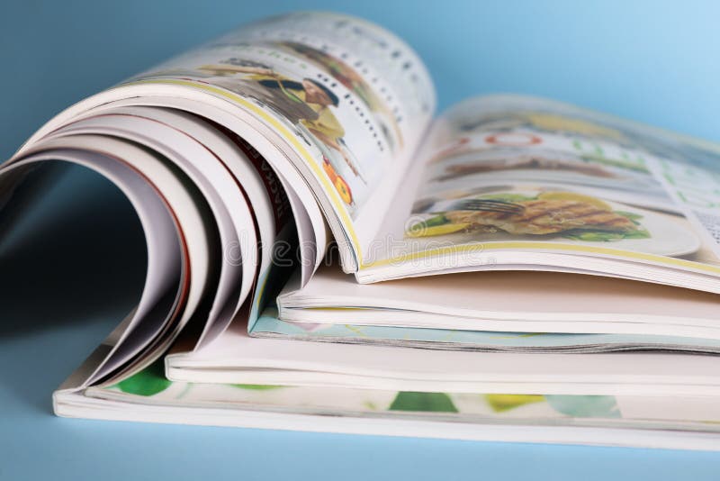 Stack of magazines on light blue background, closeup