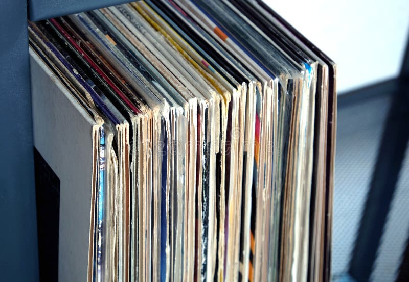 Stack of Many Vinyl Records in Old Color Covers on a Shelf Side View