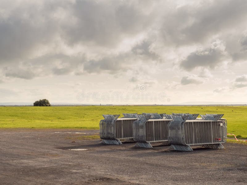 Stack of metal fences in by a green field, Cloudy sky, Concept big public event preparation and crowd and safety control stock photo