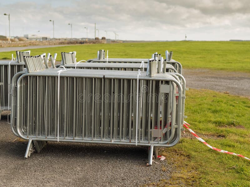Stack of metal fences in by a green field, Cloudy sky, Concept big public event preparation and crowd and safety control royalty free stock photo