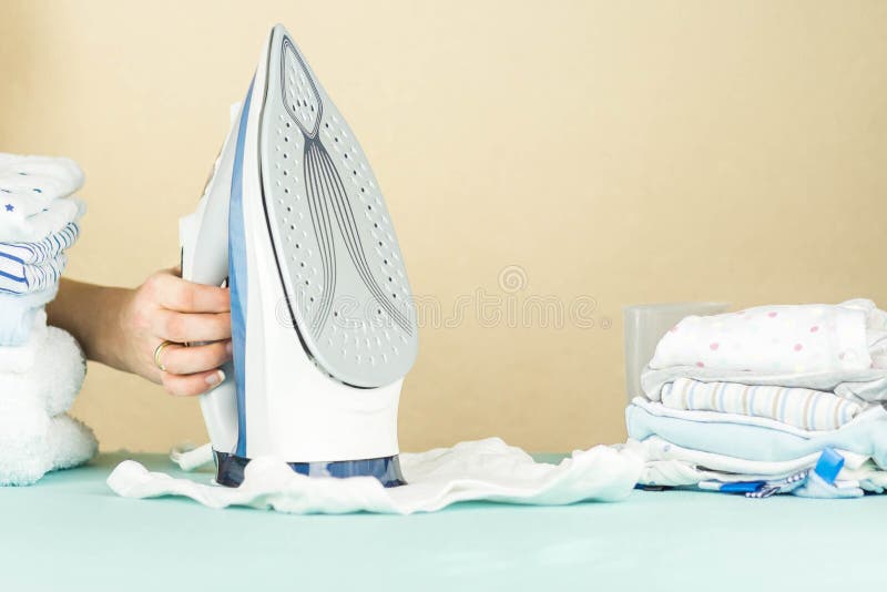 Stack of Newborn Baby Clothes Pressed with an Electric Iron Stock Image