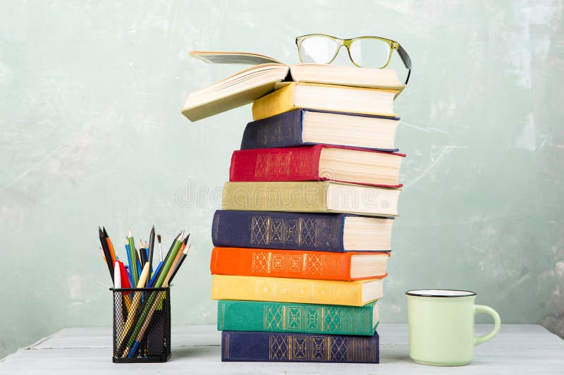 A stack of old color books, glasses, stationery on a table