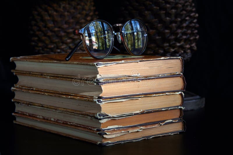Stack of Old Dusty Books, Glasses and Book Holders on a Dark Background