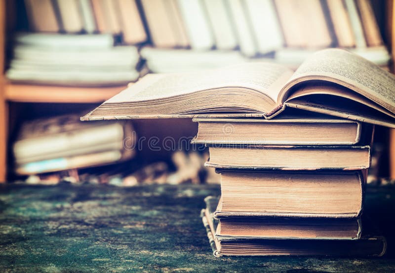 Stack of open books on aged table in the library