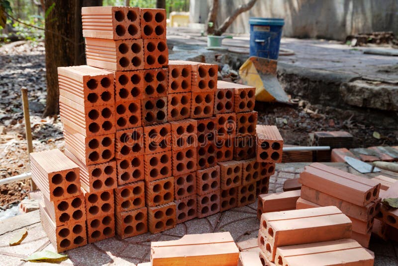 Stack of orange hollow bricks along with brick laying tools at a construction site stock image