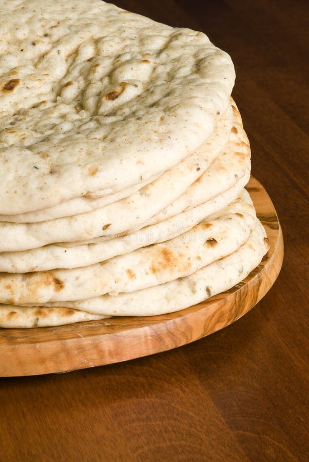 A stack of pita/naan bread on a cutting board. A stack of pita/naan bread on a cutting board.