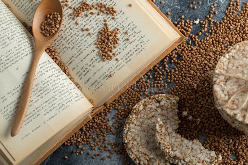 Stack of Rice Cakes , Book and Uncooked Buckwheat on Marble Surface
