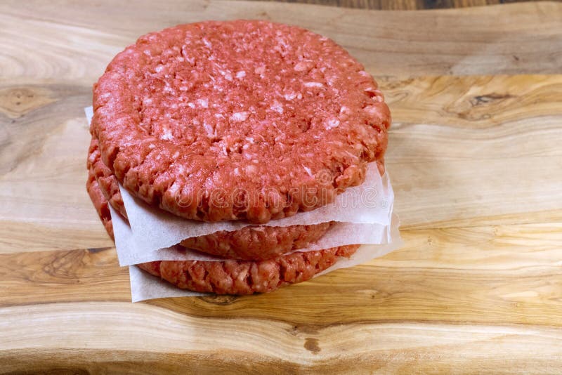 Stack of Three Fresh Uncooked Beef Burgers Separated with Cooking Paper ...