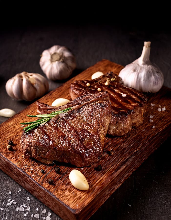 Fried steak pieces on a wooden board and garlics royalty free illustration