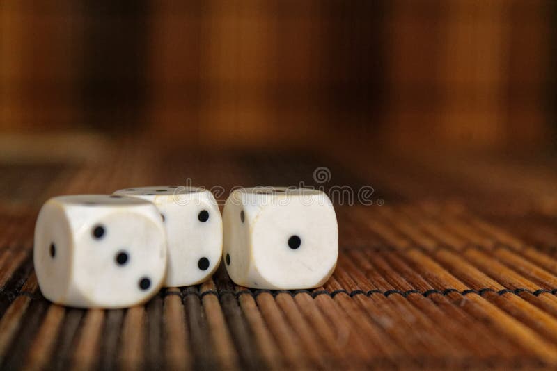 Stack of three white plastic dices on brown wooden board background. Six sides cube with black dots. Number 1, 3 royalty free stock photo Stack of three white plastic dices on brown wooden board background. Six sides cube with black dots. Number 1, 3 royalty free stock photo