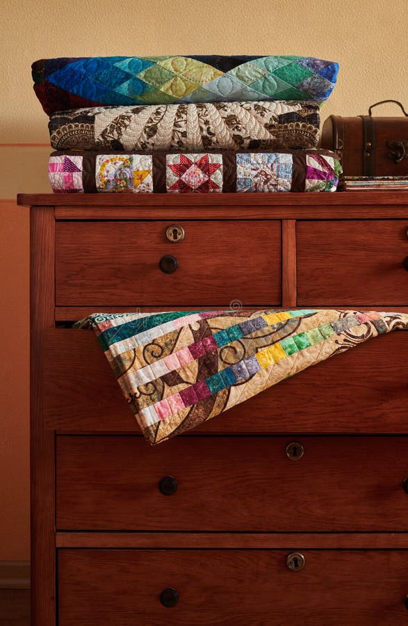 Stack Of Traditional Quilts On Chest Of Drawers Stock Photo