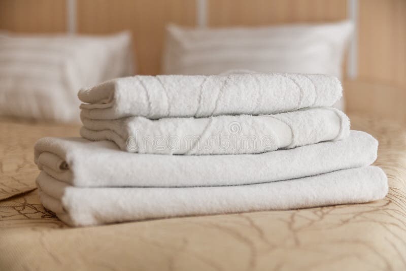 Stack of White Hotel Towel on Bed in Bedroom Interior. Stock Photo