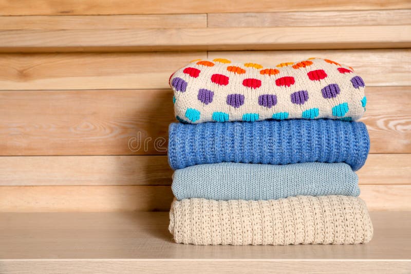 Stack of winter clothes against wooden background.
