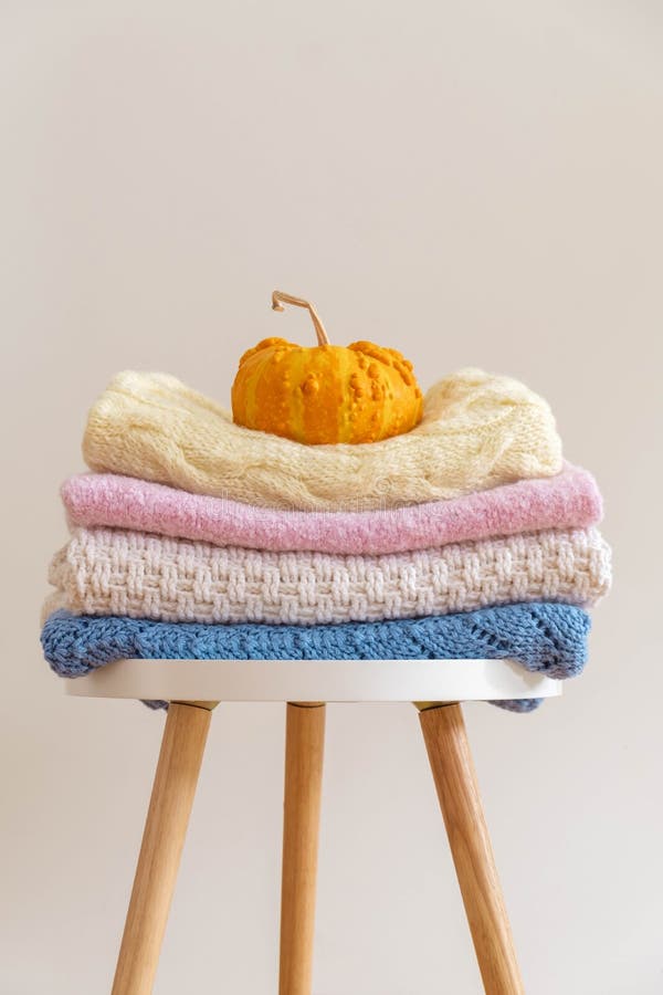 Stack of Woolen Knitted Blankets Sweaters in Pastel Colors on Neutral