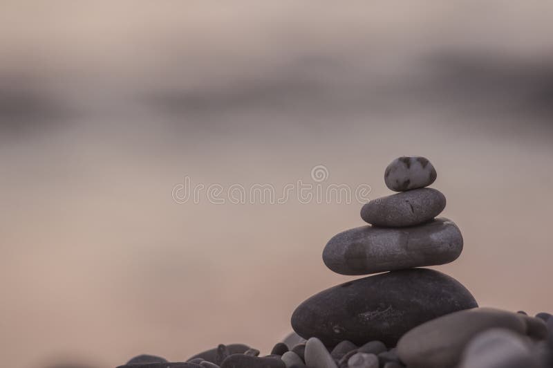 Skladané pyramída oblázek kamene na more pláž na západ slnka.