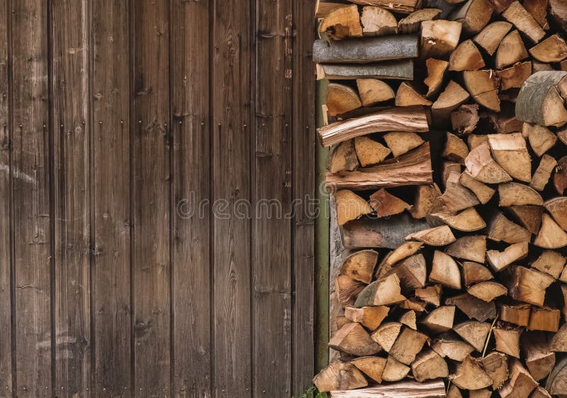 Stacked firewood near a wooden barn door