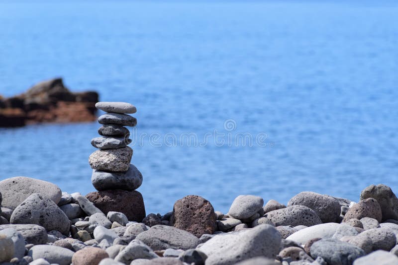 Stacked stones against on the coastline against blue water. Stacked stones on the coastline against blue water. Portuguese island of Madeira royalty free stock photos Stacked stones against on the coastline against blue water. Stacked stones on the coastline against blue water. Portuguese island of Madeira royalty free stock photos