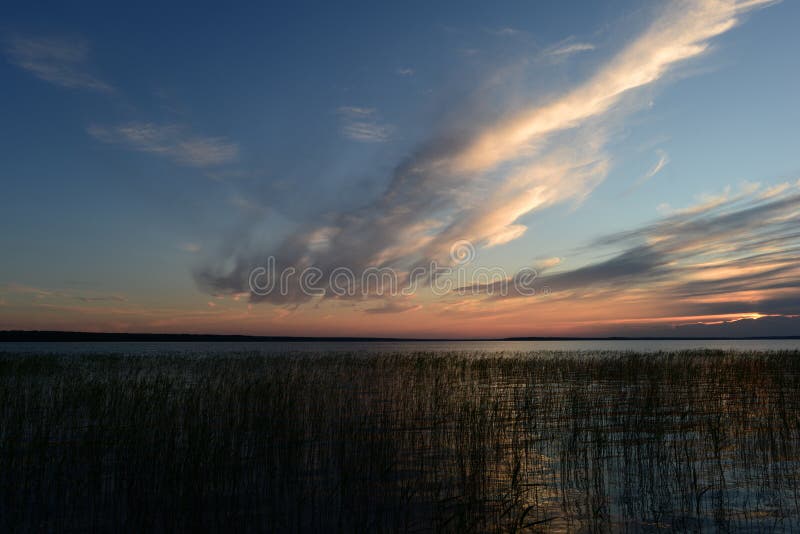 Stackmolnmoln faller från himlen in i sjön bak vasserna på solnedgången arkivbilder