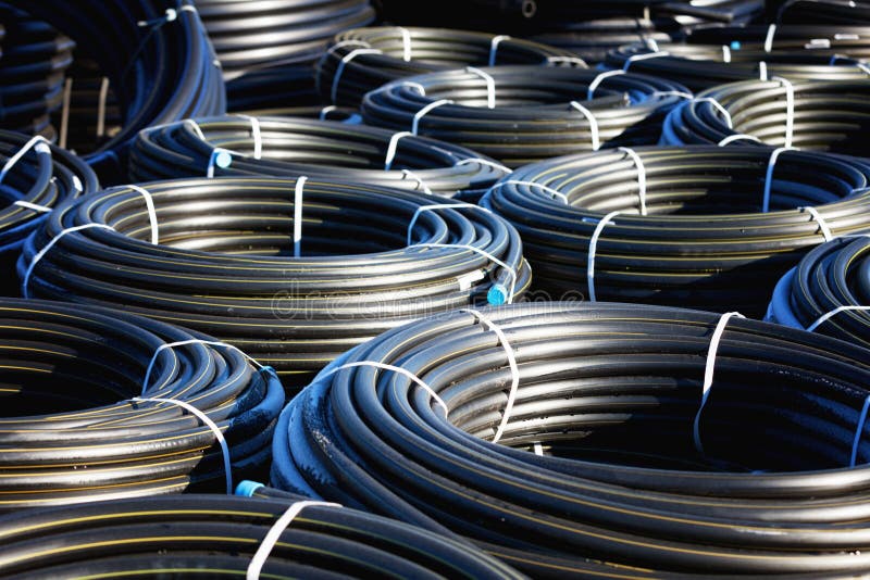 Stacks of Black Pvc Plastic Pipe Outdoors with Selective Focus Stock
