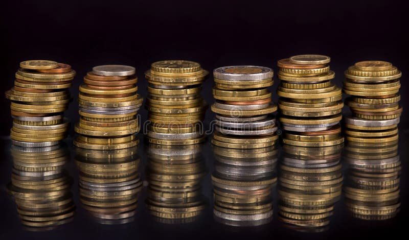 Stacks cf different country coins on black background