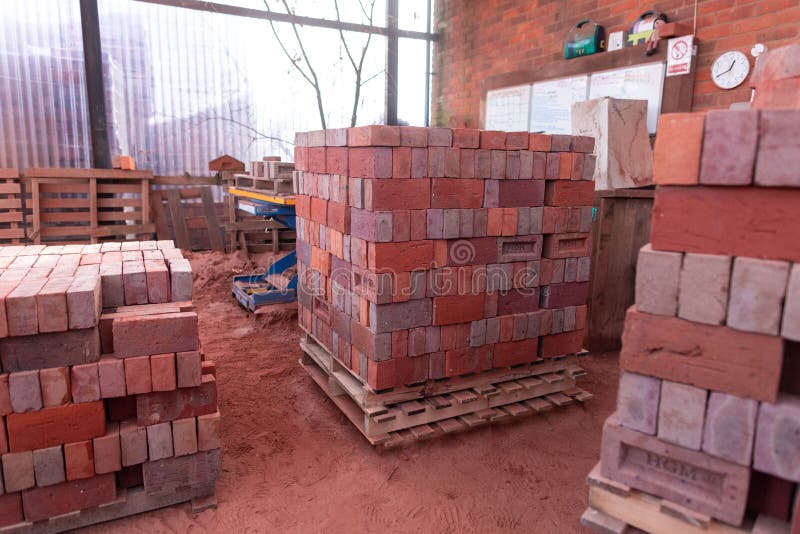 Stacks of Red Bricks and Pallets with a Clock Displayed on a Windowsill