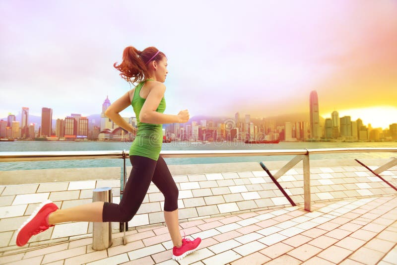 Stads- löparekvinna som joggar i Hong Kong på solnedgången arkivbild Stads- löparekvinna som joggar i Hong Kong på solnedgången arkivbild