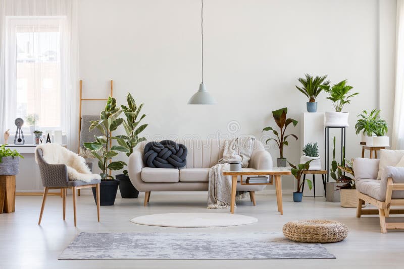 Stadscerne in trendy woonkamer binnenin met witte bank met zwarte knot kussen en houten meubelruimte op lege wand Stadscerne in trendy woonkamer binnenin met witte bank met zwarte knot kussen en houten meubelruimte op lege wand