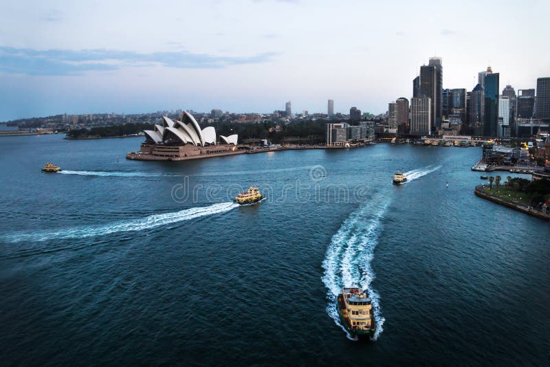 Stadtbild von Sydney mit Opernhaus und von Fähren im Ozean nach Sonnenuntergang, Sydney, Australien