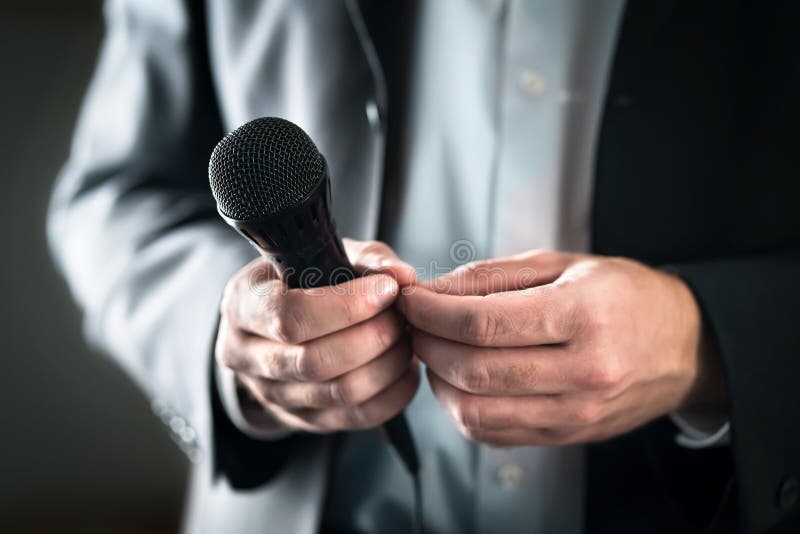 Stage fright concept. Nervous and shy public speaker with microphone. Business man afraid of giving speech for crowd of people.