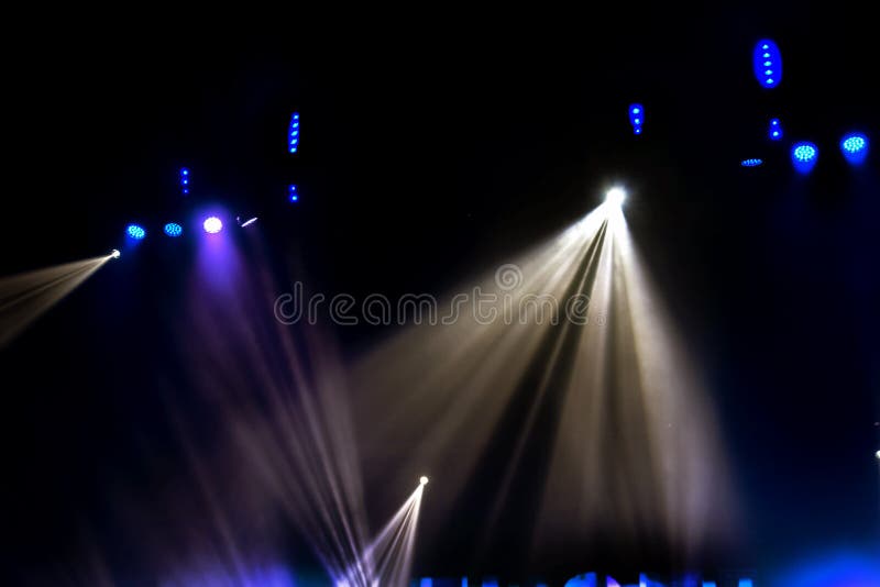 Stage lights. Several projectors in the dark. Multi-colored light beams from the stage spotlights on the stage in the smoke at the.