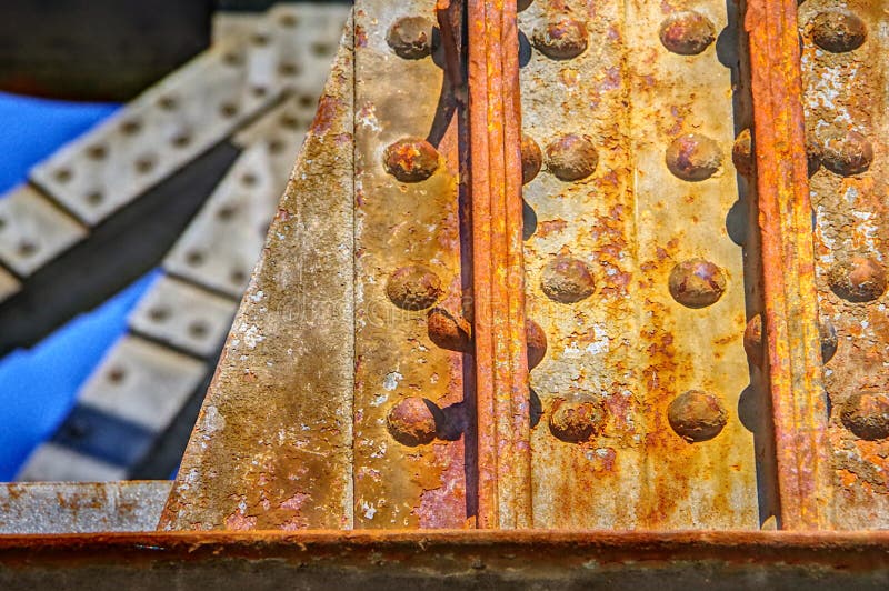 Stahlträger mit Fliegerost einer Eisenbahnbrücke. Rostiger Stahlträger vor blauem Himmel, schwere Brückenkomponenten mit bereifter Oberfläche, Stahlstempel mit Frost verrosten vor blauem Himmel, Detail einer Eisenbahnbrücke, moderner Brückenbau,