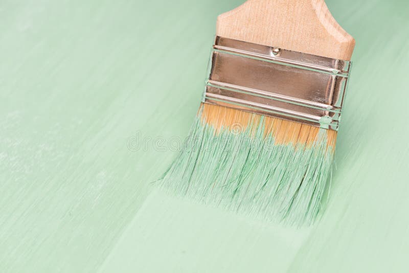 Staining Wood Surfaces with Green Paint Using a Paint Brush Stock Photo