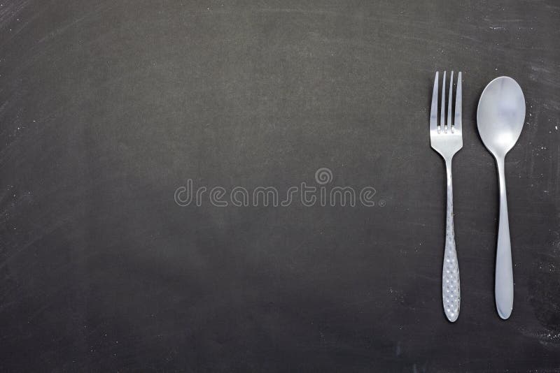 Stainless steel spoon and fork on black wood or chalkboard background stock images Stainless steel spoon and fork on black wood or chalkboard background stock images