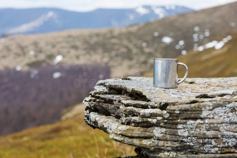 Stainless steel thermo mug on a flat stone within tne mountains royalty free stock photography Stainless steel thermo mug on a flat stone within tne mountains royalty free stock photography