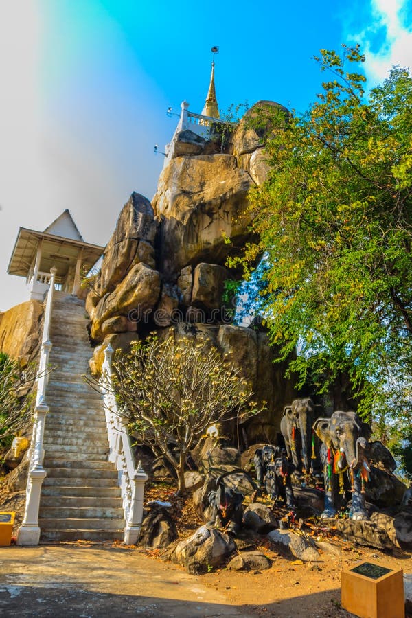 Stair way upward to the golden pagoda on the hill with blue sky background at Wat Khao Rup Chang or Temple of the Elephant Hill, o