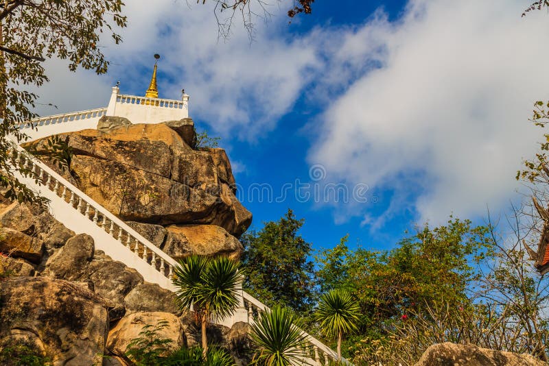 Stair way upward to the golden pagoda on the hill with blue sky background at Wat Khao Rup Chang or Temple of the Elephant Hill, o