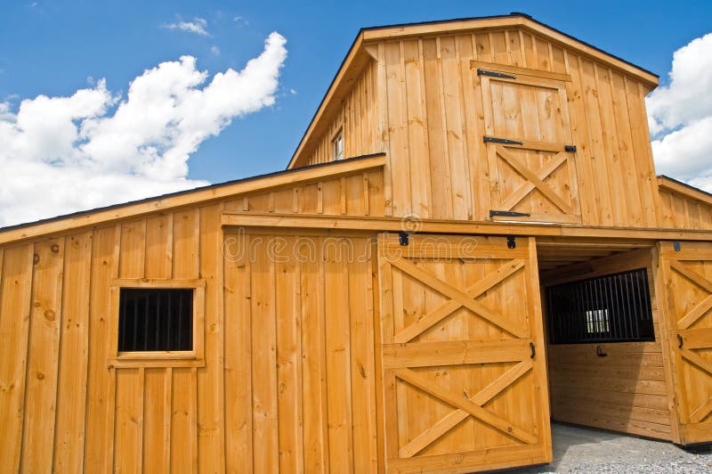 A view of a new wooden farm barn with sliding doors and a second story. A view of a new wooden farm barn with sliding doors and a second story.