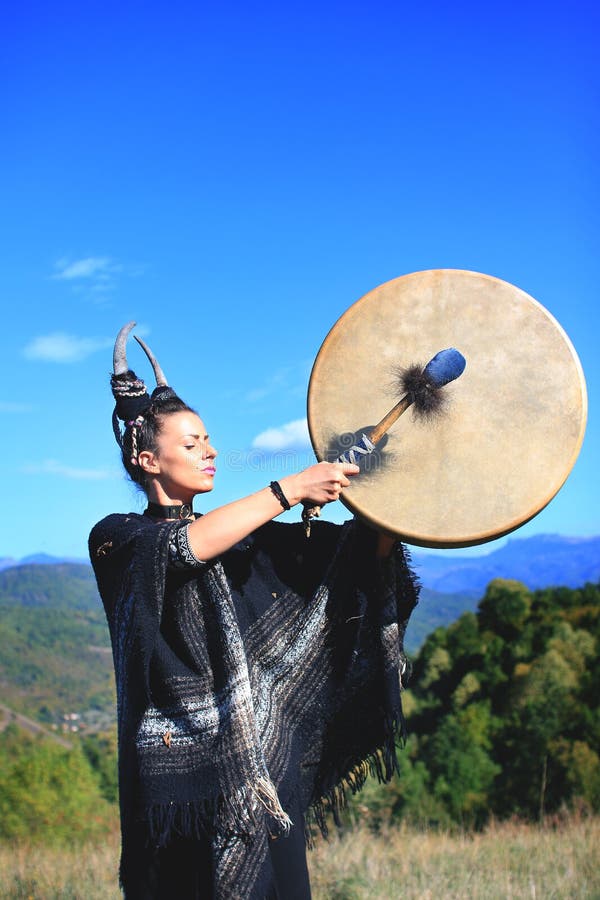 Stam- kvinna med horn som spelar en buffelvals på berget royaltyfria foton Stam- kvinna med horn som spelar en buffelvals på berget royaltyfria foton