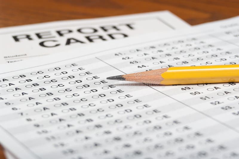 Standardized test with a yellow pencil and report card on a wooden desktop. Standardized test with a yellow pencil and report card on a wooden desktop.