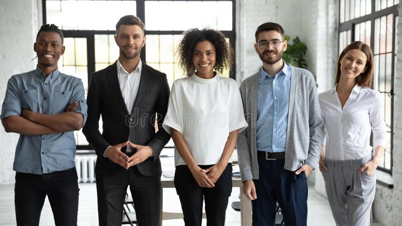 Standing in row smiling diverse team posing differently. royalty free stock photo
