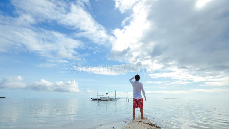 Standing young man looks at horizon on beach stock photos
