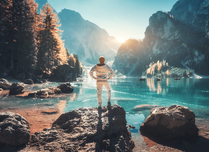 Standing young man on the stone on the coast of Braies lake