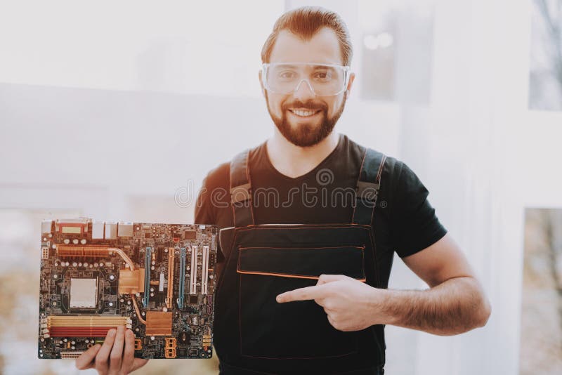 Standing Young Worker with Motherboard in Hand.