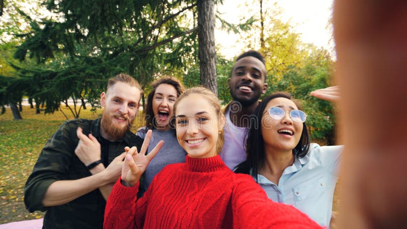 Standpunt van het jonge apparaat van de vrouwenholding met camera en het nemen selfie met vrienden multi-etnische groep wordt ges royalty-vrije stock foto Standpunt van het jonge apparaat van de vrouwenholding met camera en het nemen selfie met vrienden multi-etnische groep wordt ges royalty-vrije stock foto