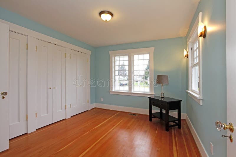 Stanza blu con il pavimento della ciliegia ed i portelli bianchi dell'armadio
