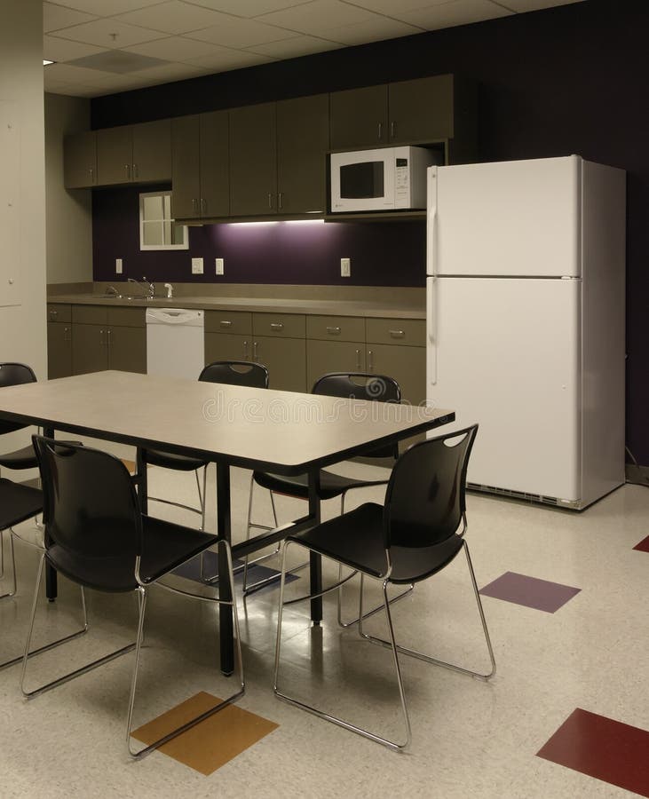 Interior of an generic office break room cafe and kitchen area with meeting workspace and accent purple wall, plastic office chairs and plastic laminate tables - empty of people - employees kitchenette Office Space. Interior of an generic office break room cafe and kitchen area with meeting workspace and accent purple wall, plastic office chairs and plastic laminate tables - empty of people - employees kitchenette Office Space